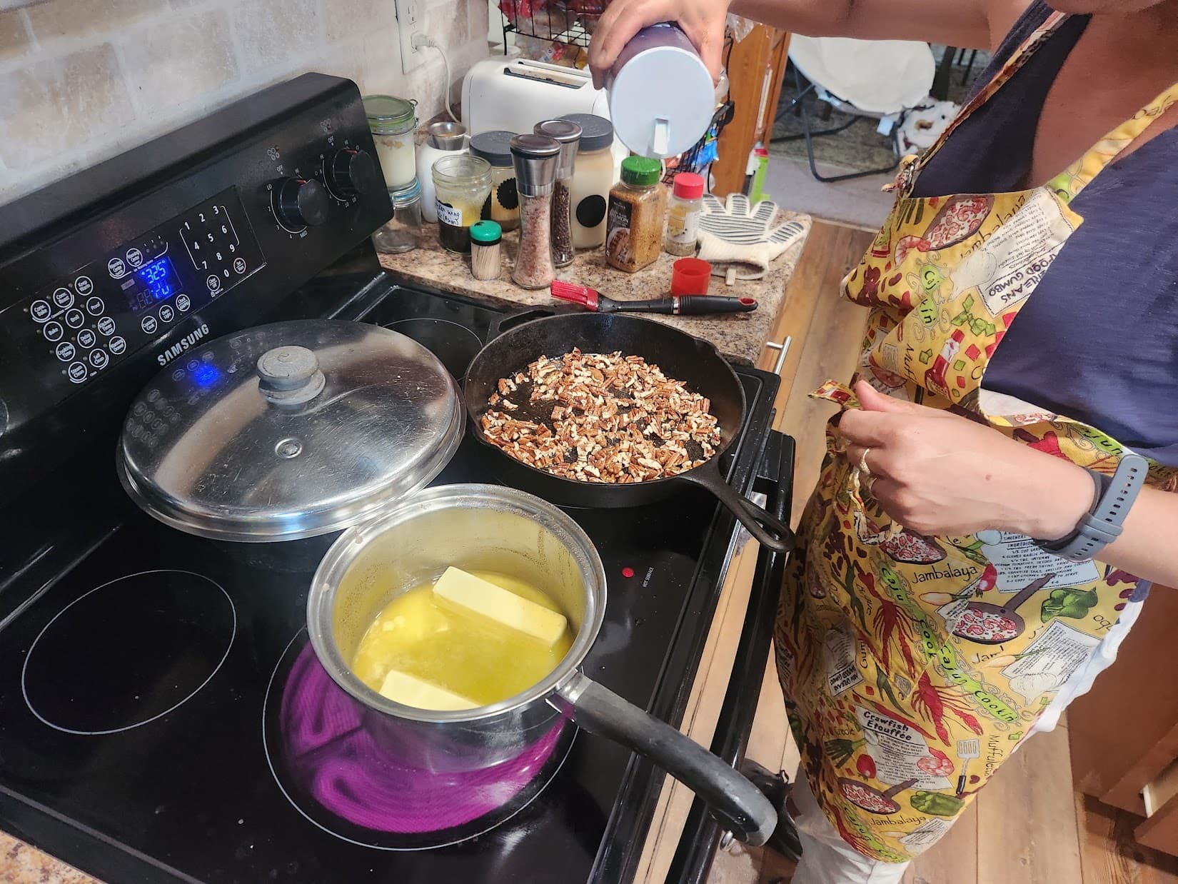 Missy at the stove toasting pecans in a cast-iron skillet next to a pot of melting butter.